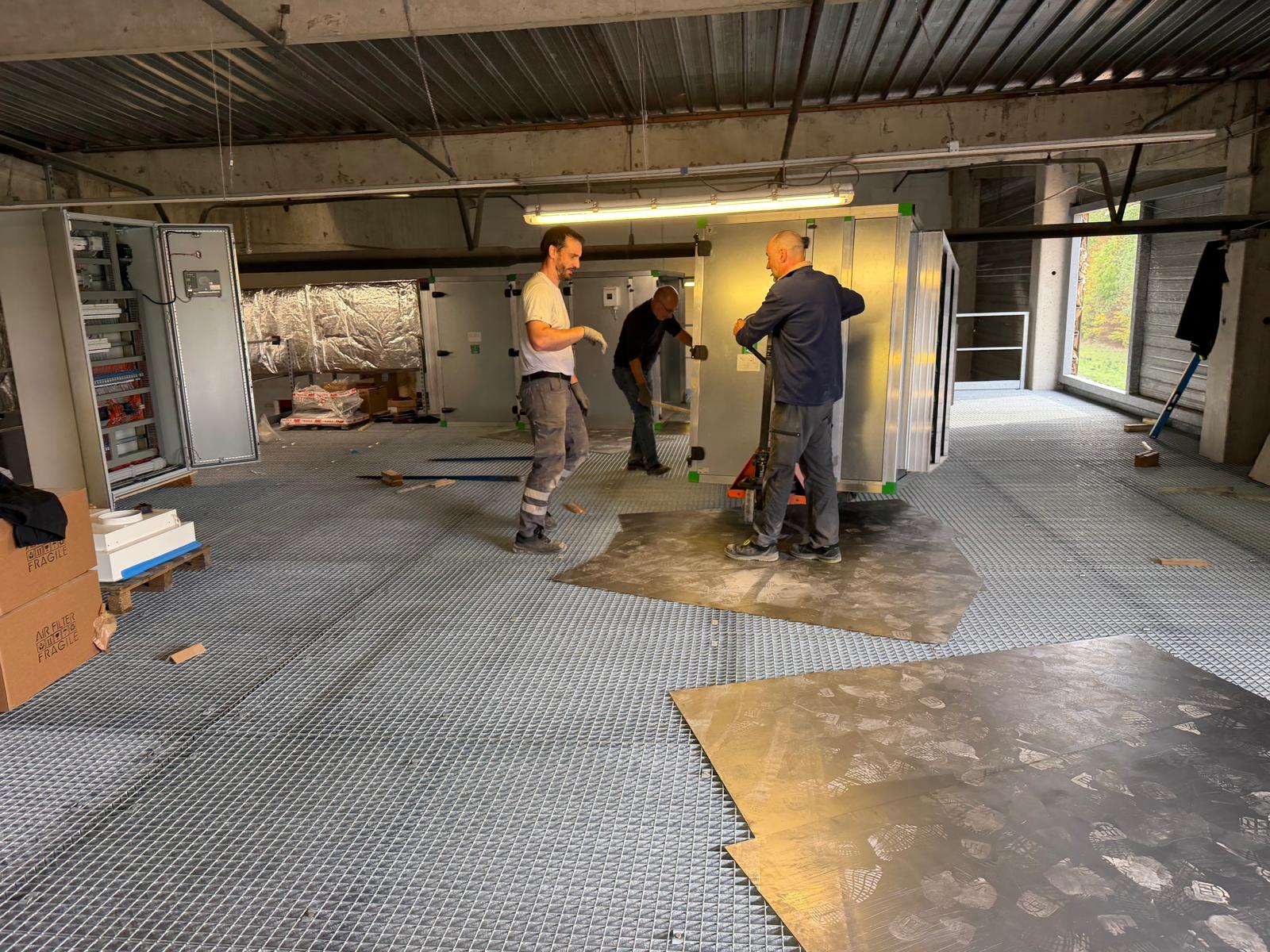 Techniciens positionnant une centrale de traitement d’air sur la mezzanine technique